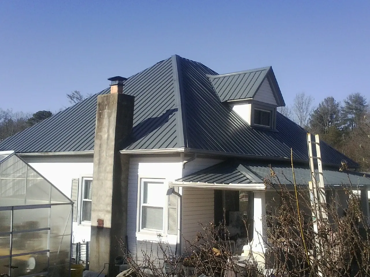 Dark blue standing seam metal roof on a white farmhouse with dormer — Slate & Tile Roof Repair by Roofing Brothers in Kingsburg
