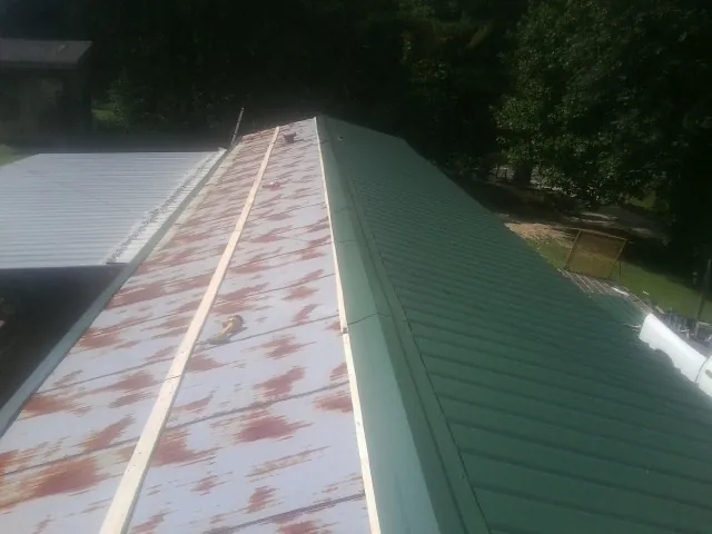 Old rusted panels beside newly installed green metal roofing — Wind Damage Roof Repair by Roofing Brothers in Kingsburg