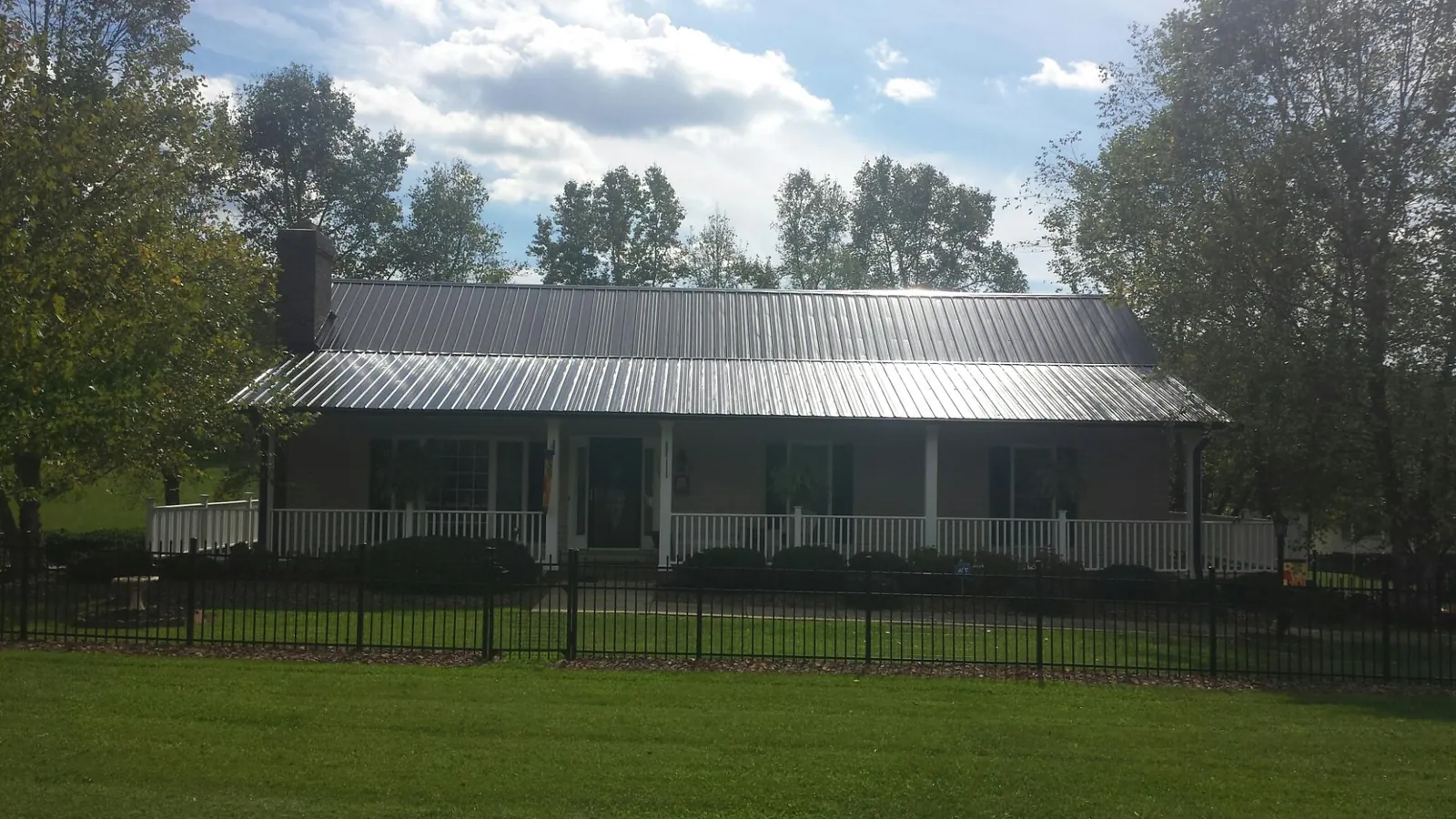 Gray metal roof on a brick ranch with a full width front porch — Gutter Guard Installation work by our crew in Kingsburg