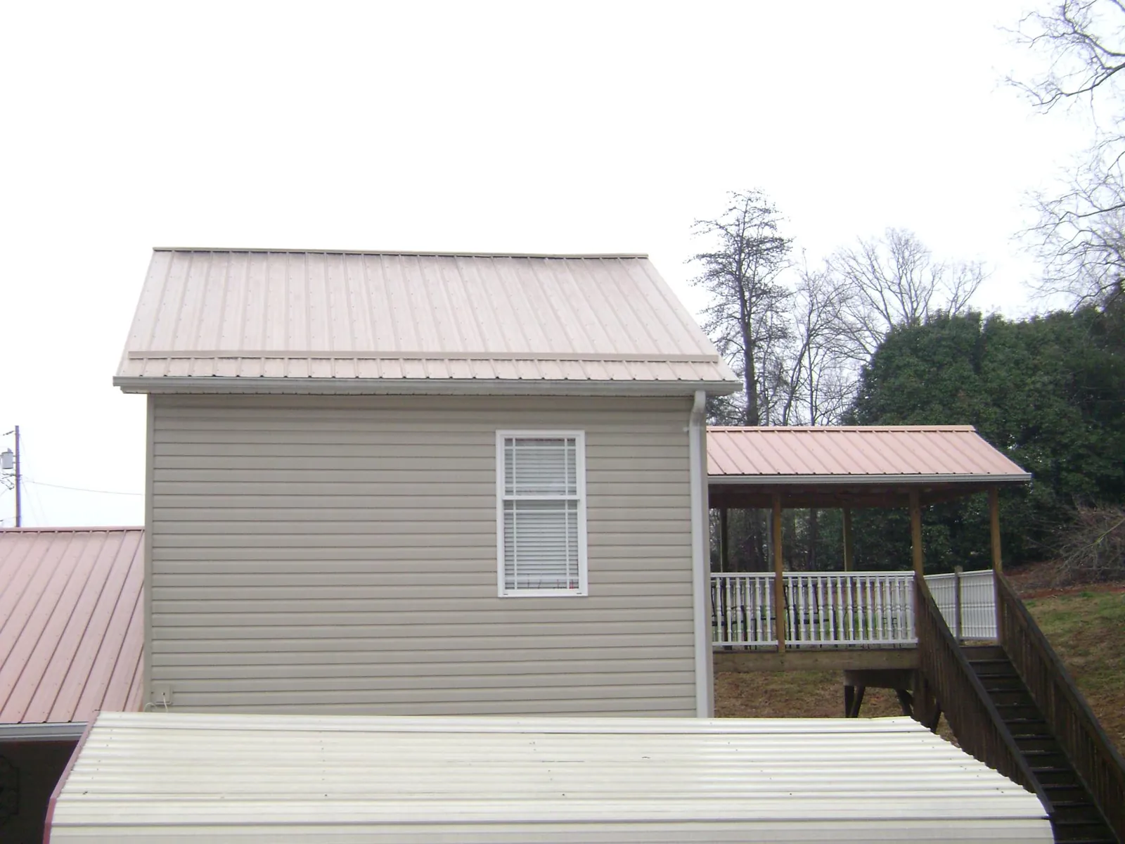 Tan metal roofs on a two story addition and attached porch, from a Roof Replacement job in Kingsburg