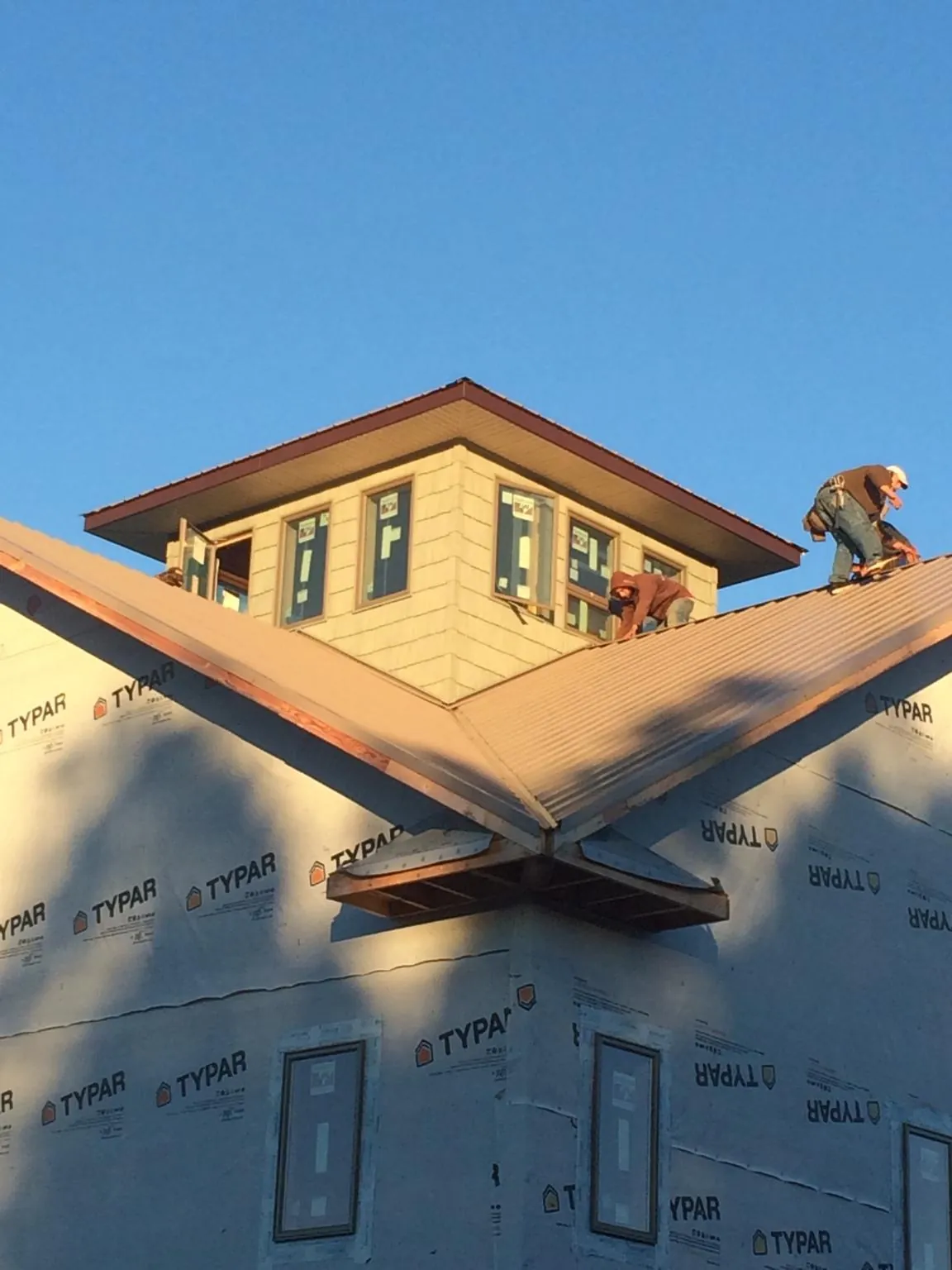 Roofers working around a rooftop cupola on a new metal roof at sunset — Roof Waterproofing in Kingsburg by Roofing Brothers